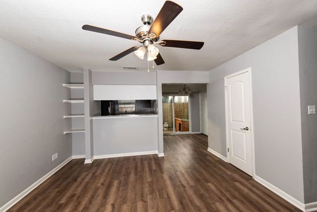 Living room with ceiling fan, built-in shelves and wood-style flooring